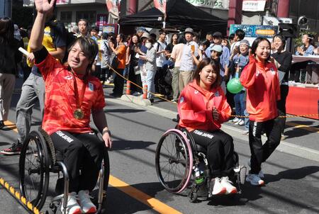 手を上げる島川選手、西田選手、高室選手が笑顔で沿道を歩いている、パレードの様子