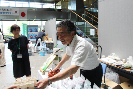 市内茶園の店主が笑顔で自らお茶をふるまう様子。